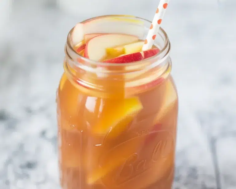 Delicious caramel apple sangria served in a festive glass, garnished with apple slices.