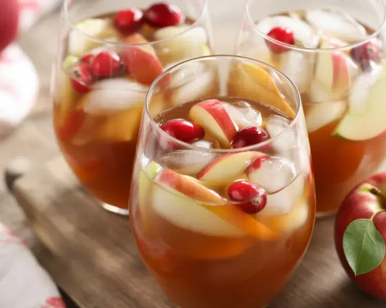 Glass of apple cider sangria with fresh fruit and cinnamon sticks
