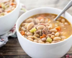 Delicious Crockpot Ham And Bean Soup with ham, white beans, and vegetables in a slow cooker