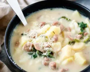 Creamy Crockpot Zuppa Toscana soup with sausage, potatoes, and kale in a rich broth.
