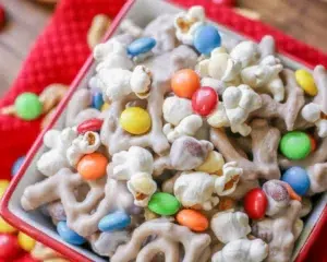 A bowl of white chocolate pretzel trail mix with Chex, M&M's, and nuts.