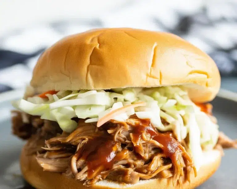 Deliciously tender Slow Cooker Pulled Pork served with BBQ sauce.