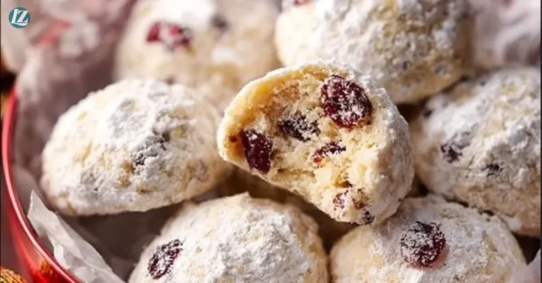 Cranberry orange snowball cookies dusted with powdered sugar on a plate.