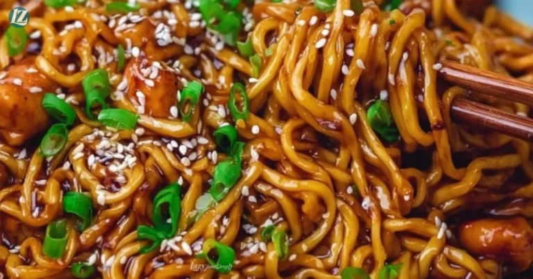 Plate of sticky garlic chicken noodles garnished with scallions and sesame seeds.