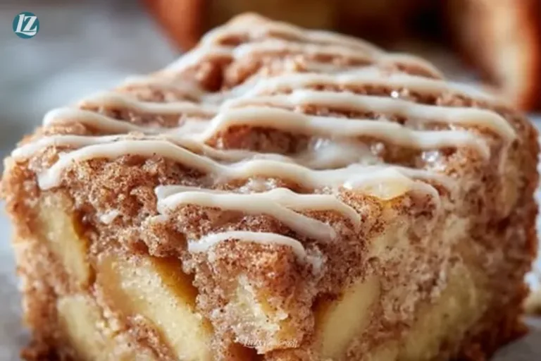 Cinnamon roll apple cake topped with icing and cinnamon, served on a plate.