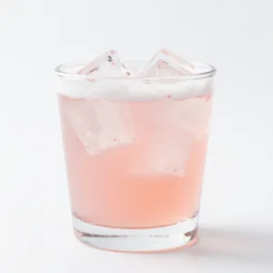 Homemade rhubarb soda served in a glass with ice and fresh rhubarb garnish.