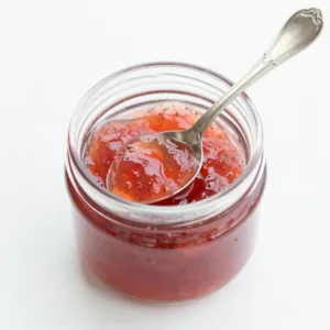 Homemade Rhubarb Vanilla Bean Jelly in a jar with fresh rhubarb stalks.